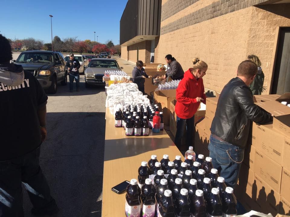 A group of people are standing around a table full of bottles of soda