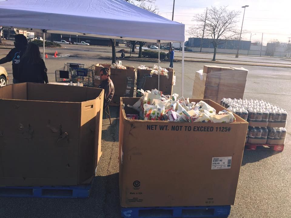 A lot of cardboard boxes are sitting on a pallet in a parking lot.