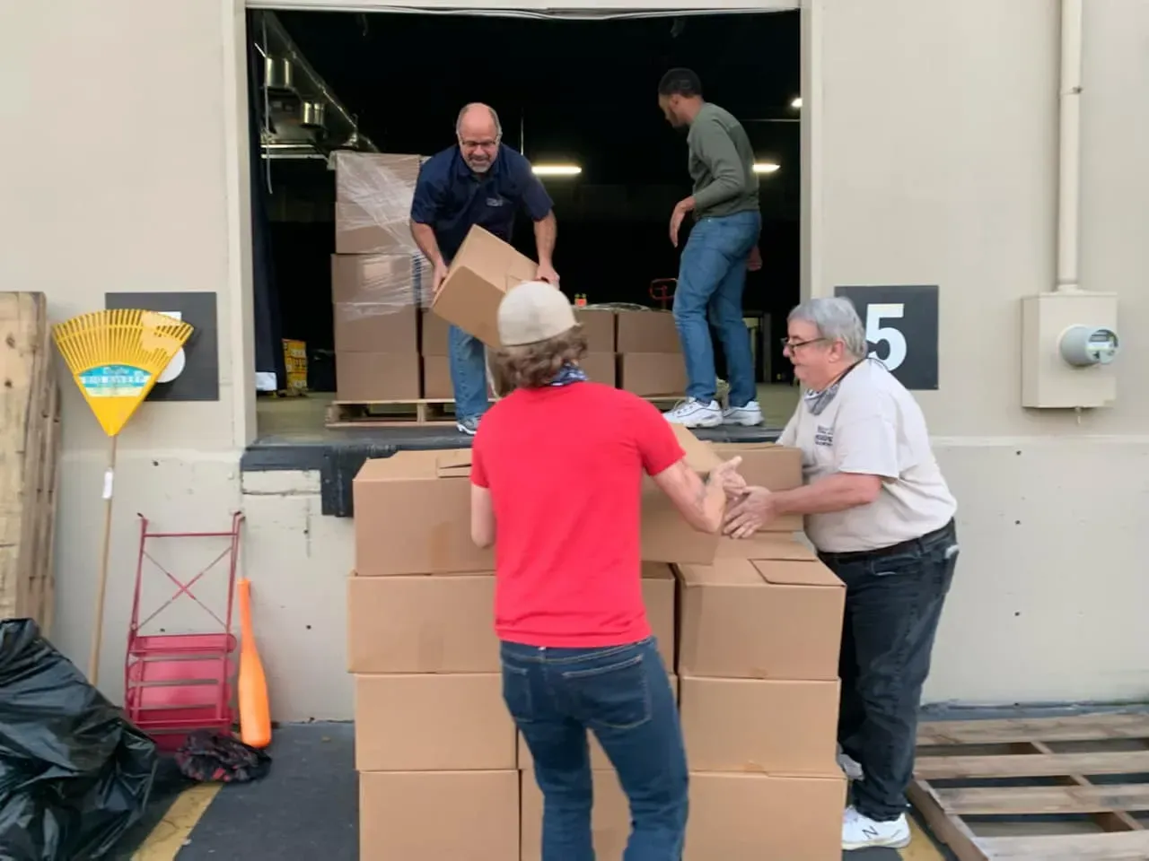 A group of men are loading boxes into a warehouse with the number 5 in the background