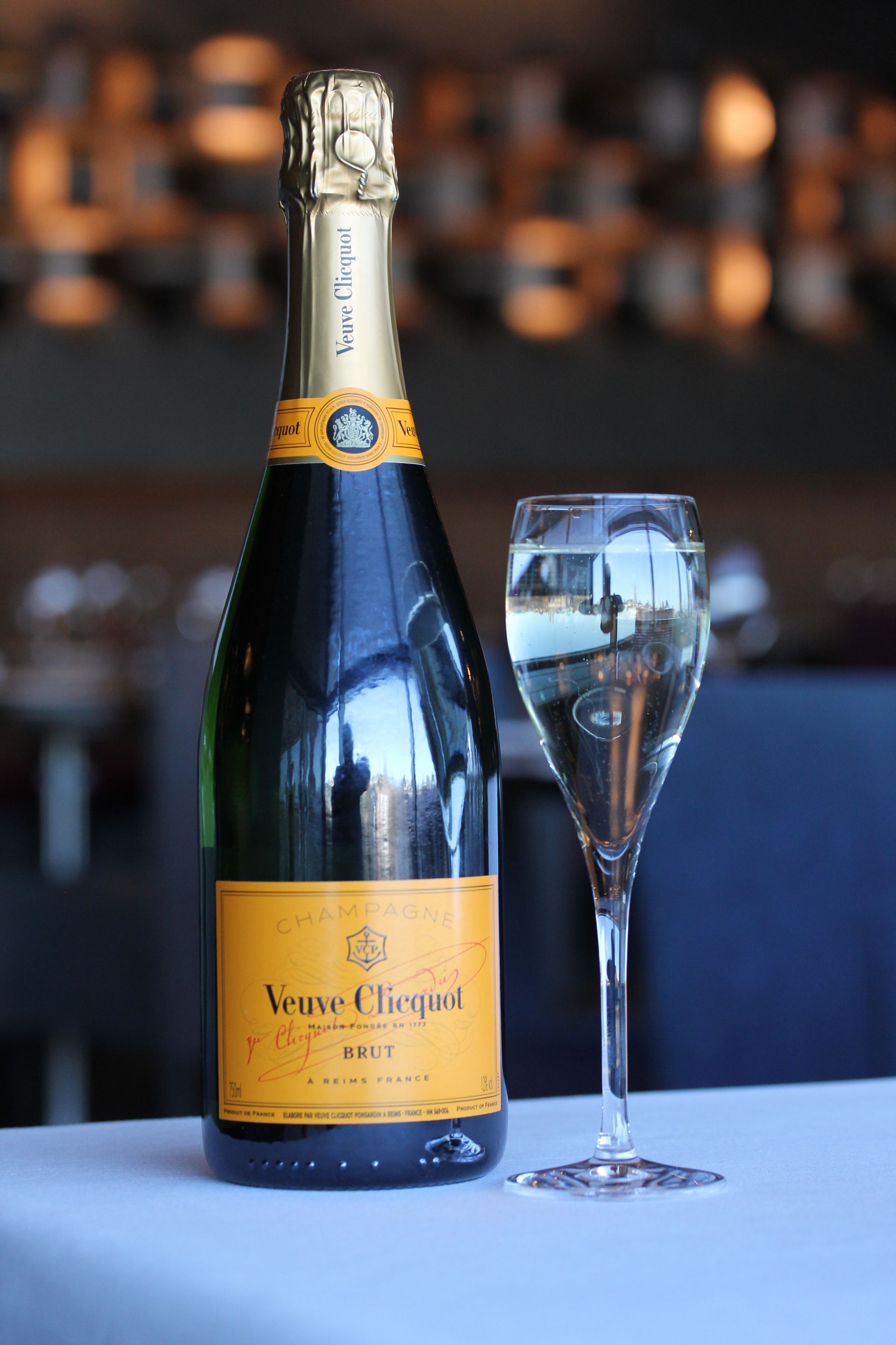 A bottle of champagne and a glass of champagne are on a table.