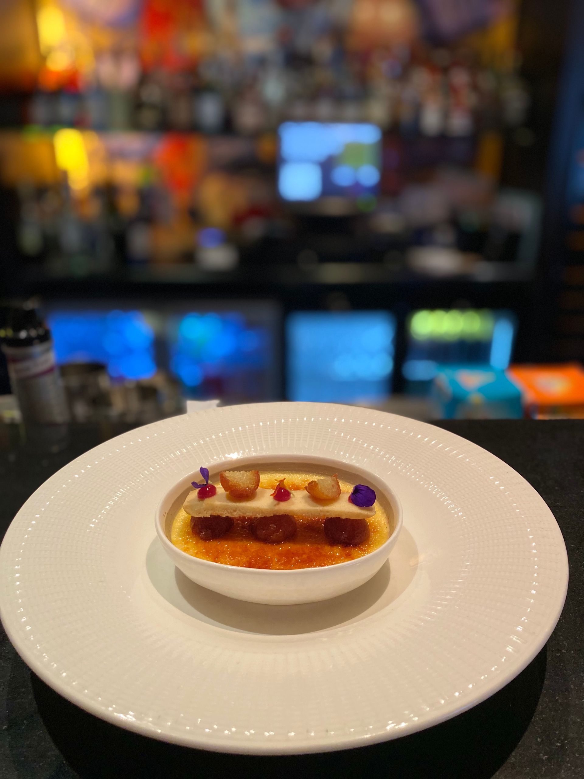 A white plate with a small bowl of food on it