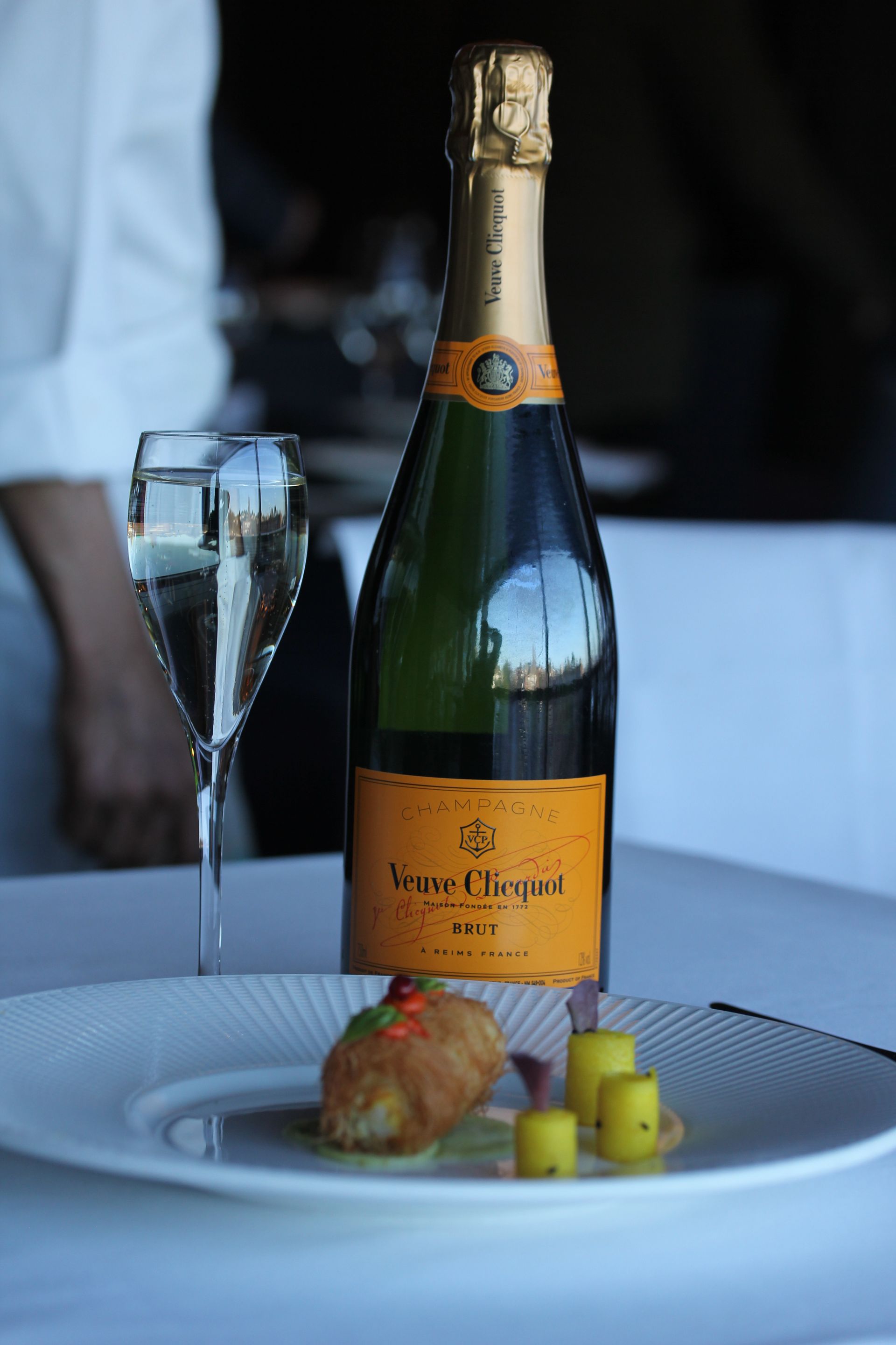 A bottle of veuve clicquot champagne is on a plate next to a glass of champagne