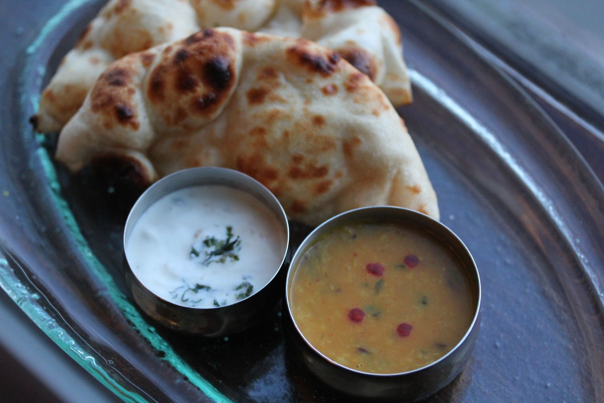 A plate of food with naan and two bowls of sauce