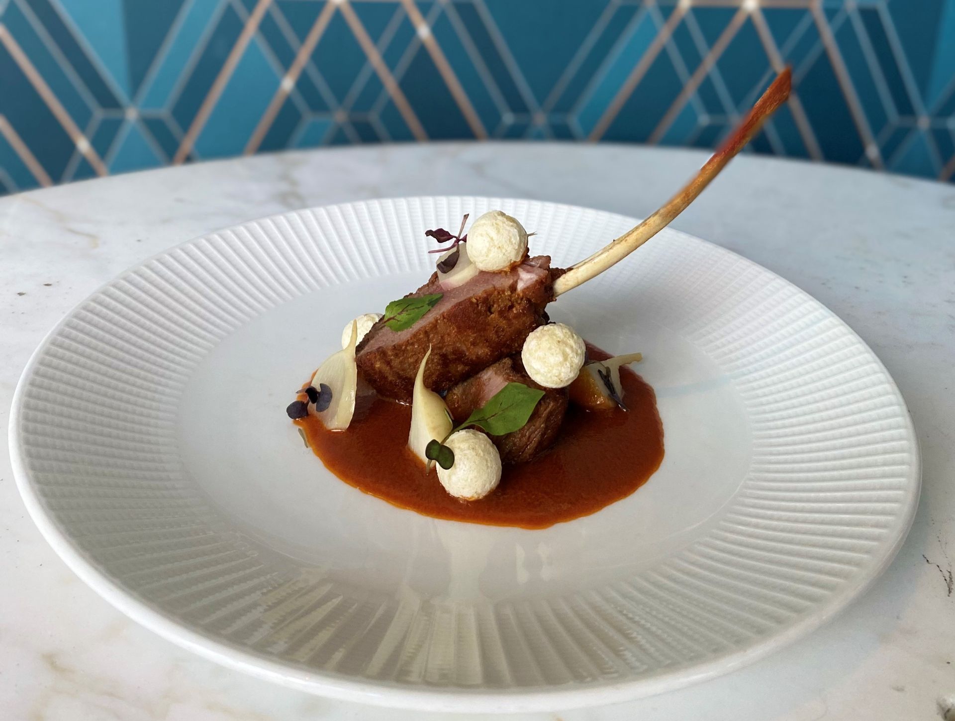 A white plate topped with meat and sauce on a table