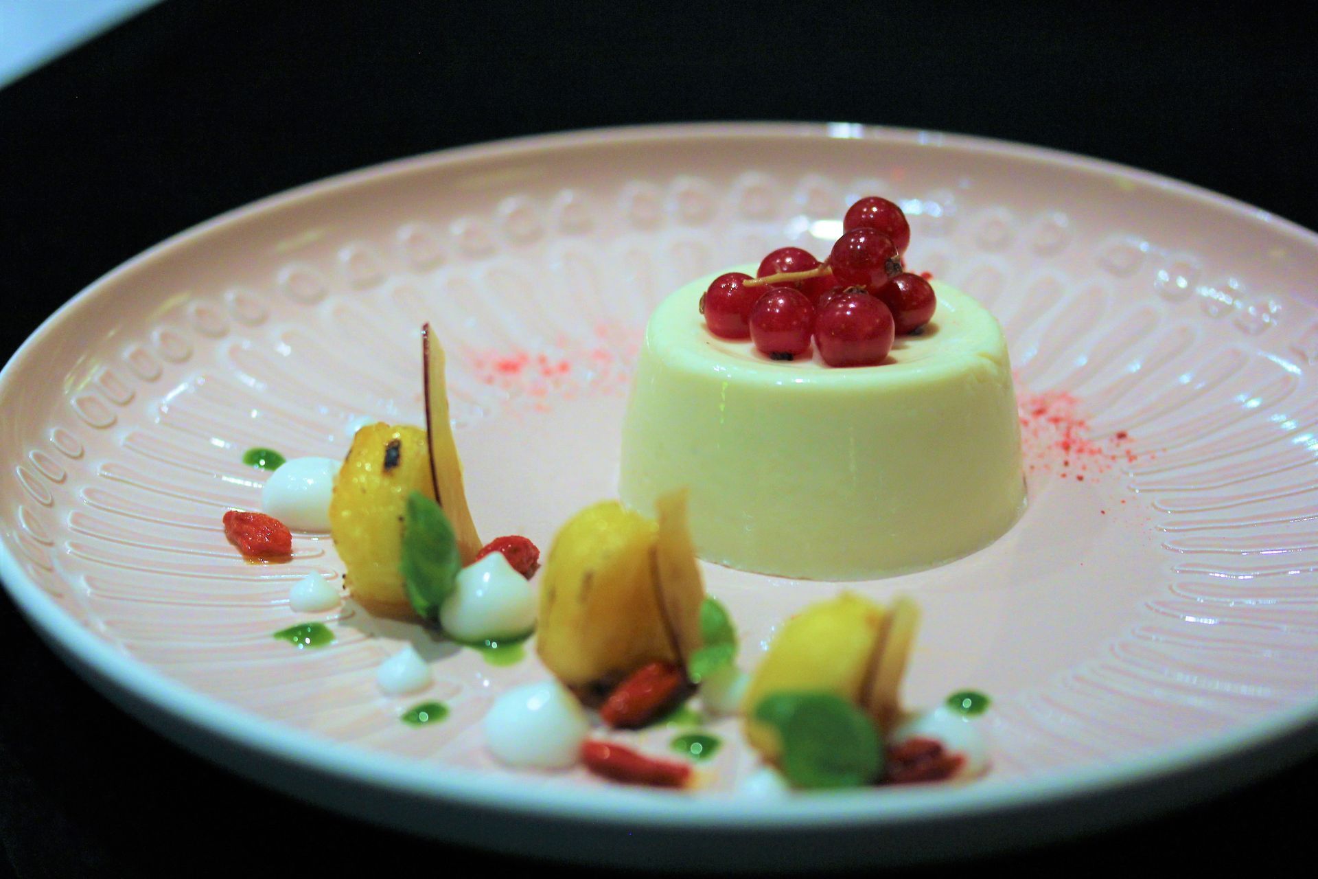 A pink plate topped with a dessert and fruit on a table.