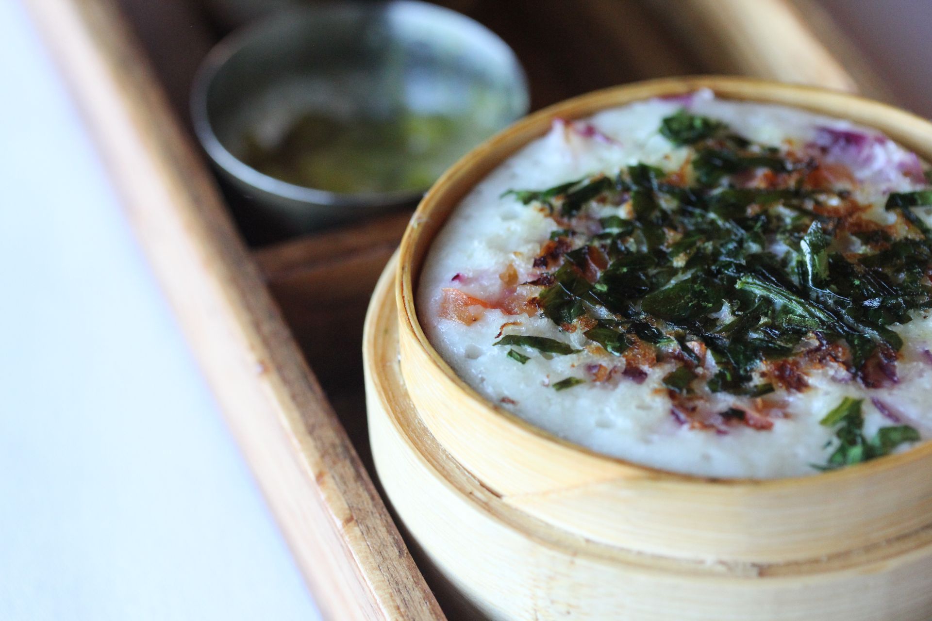 A close up of a bowl of food on a wooden tray.