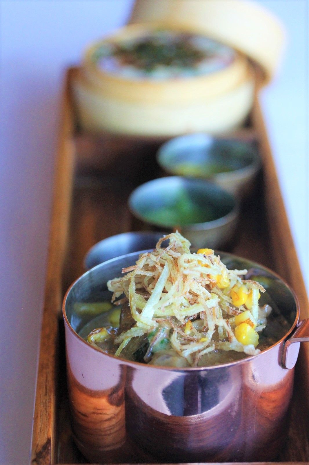 A bowl of food is sitting on a wooden tray.