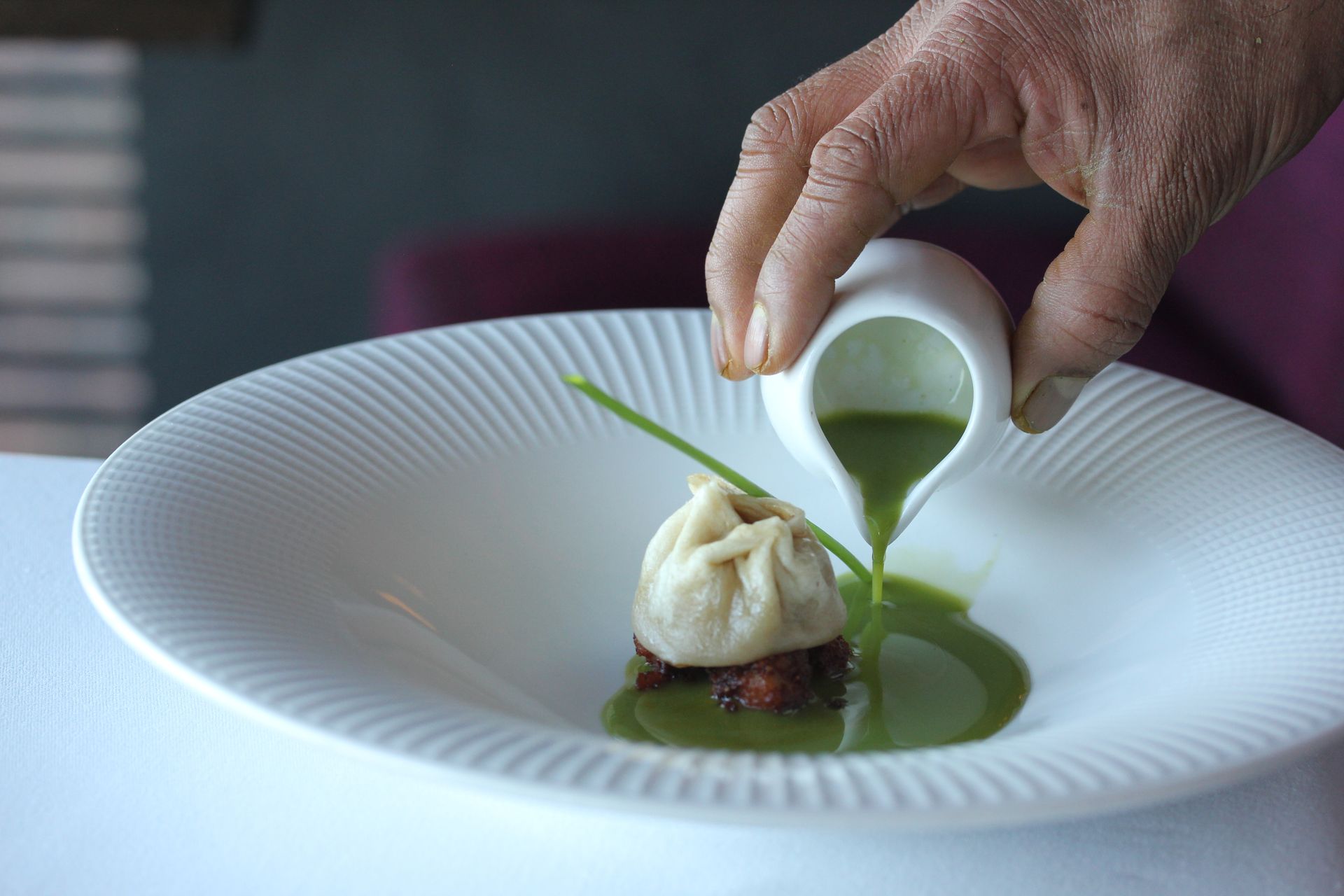 A person is pouring green liquid into a plate of food.