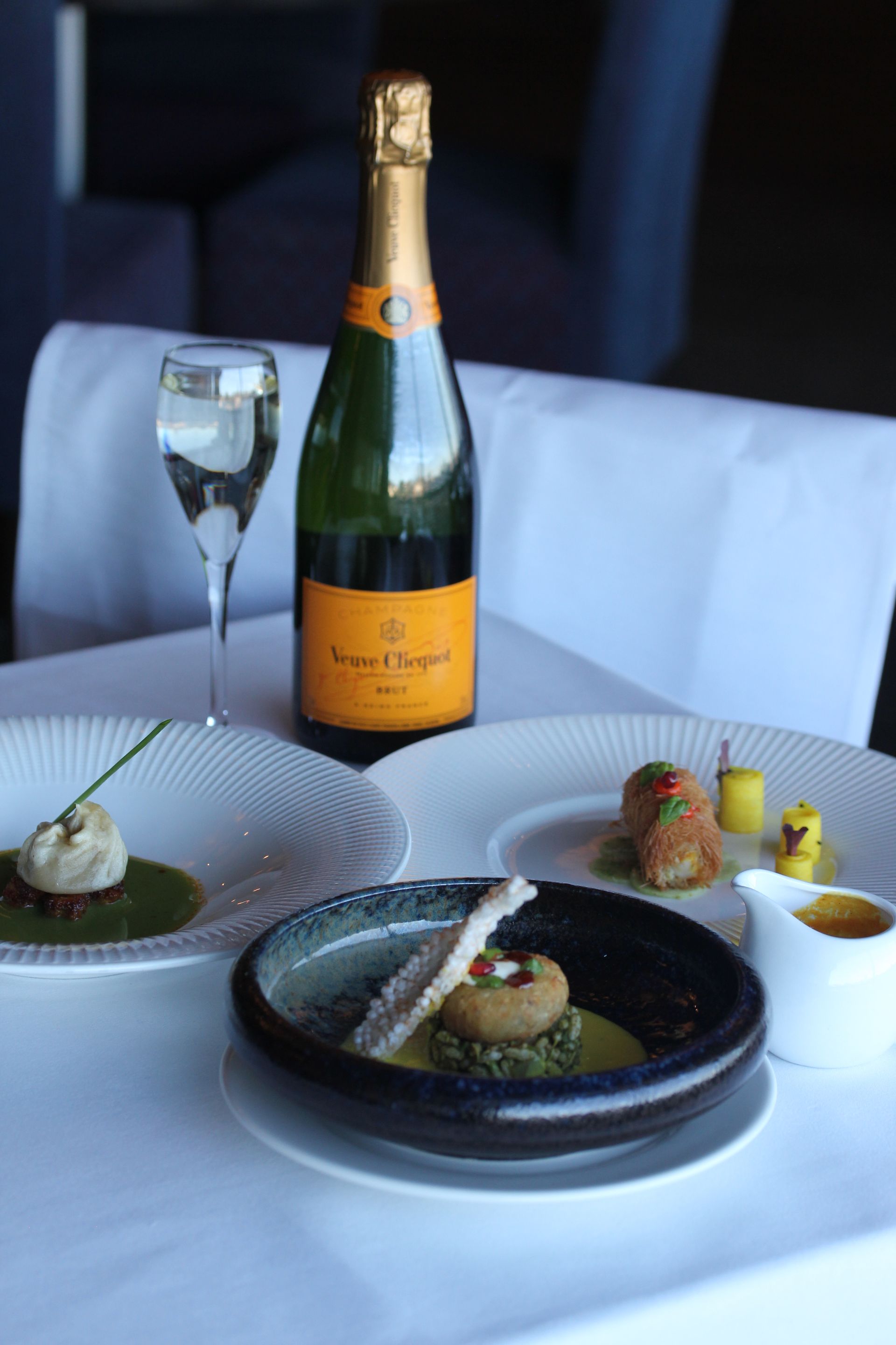 A bottle of veuve clicquot champagne sits on a table with plates of food