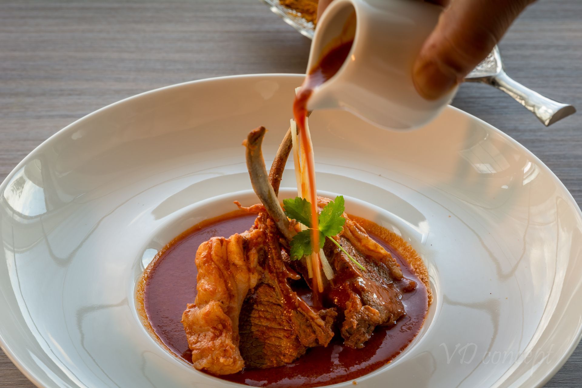 A person is pouring sauce on a plate of food