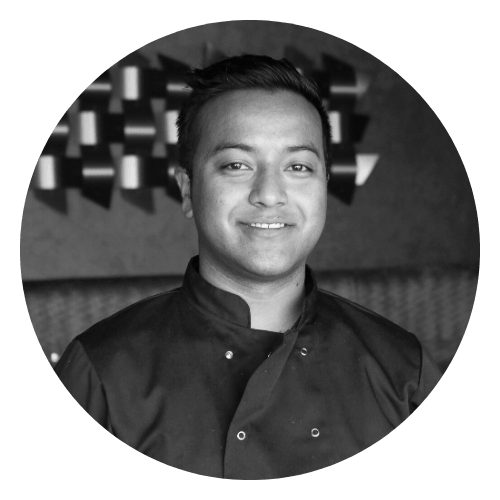 A man in a chef 's uniform is smiling in a black and white photo.