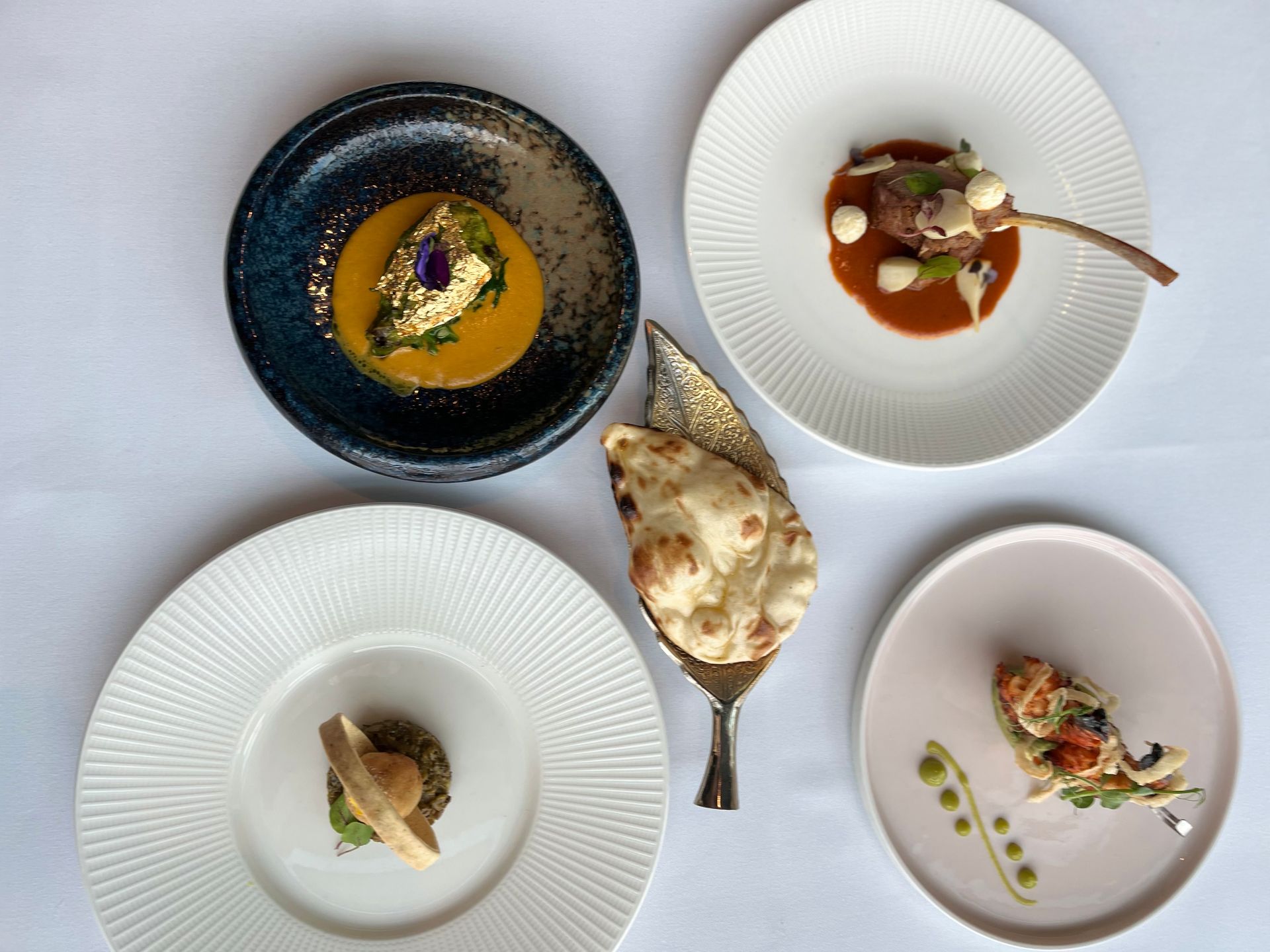 Four plates of food are sitting on a table.