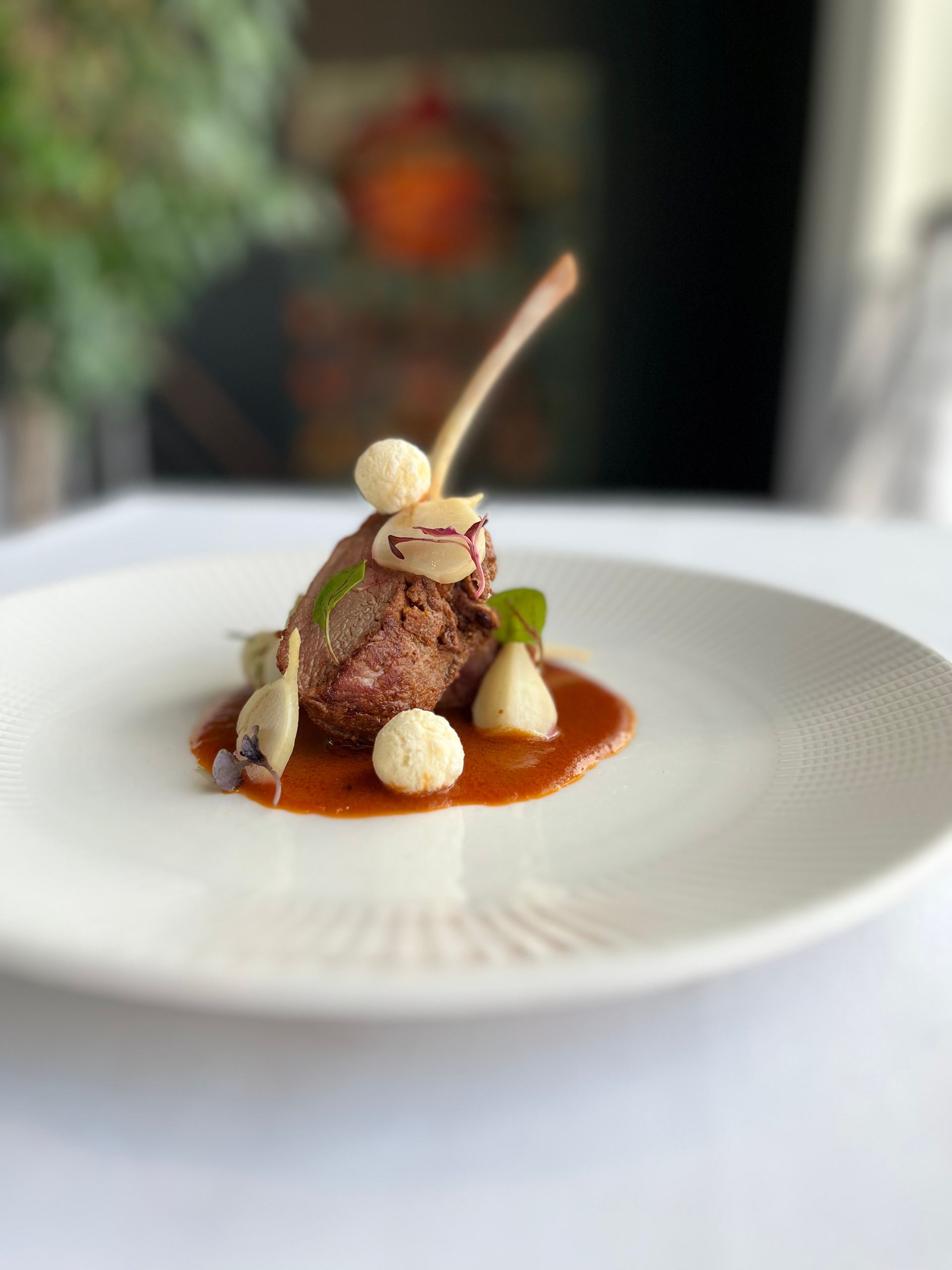 A white plate topped with a piece of meat and sauce on a table.