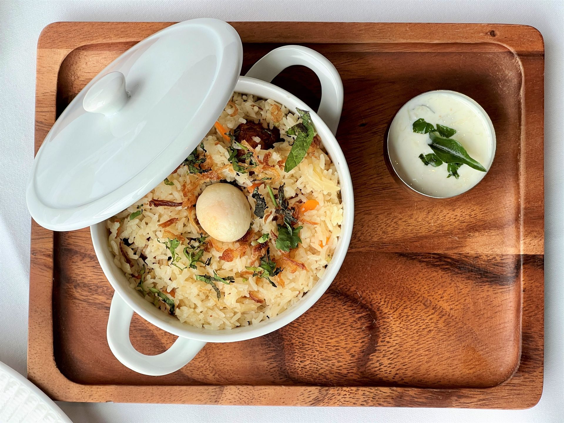 A bowl of food is sitting on a wooden tray.