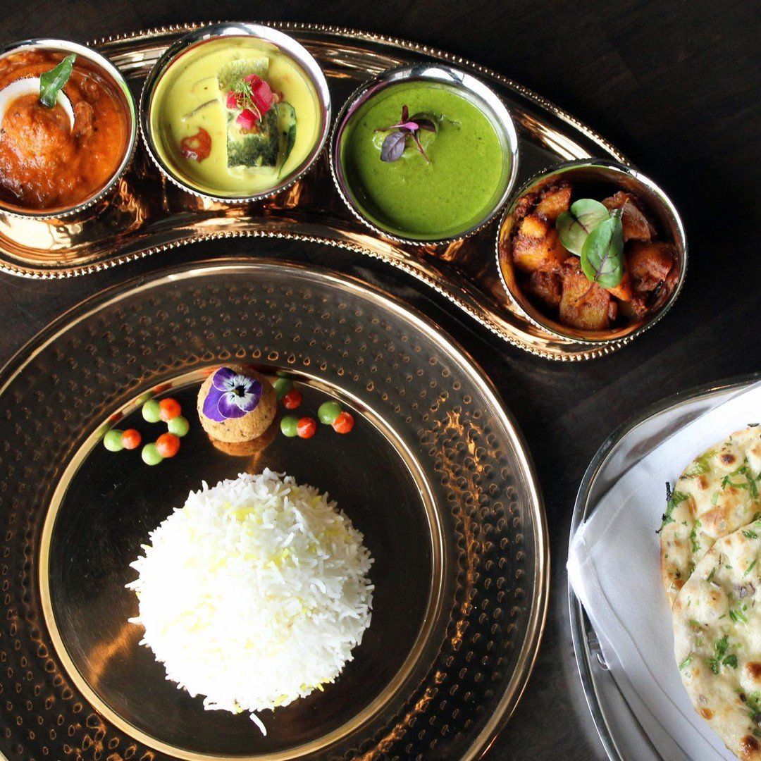 A plate of rice sits on a table next to a plate of food