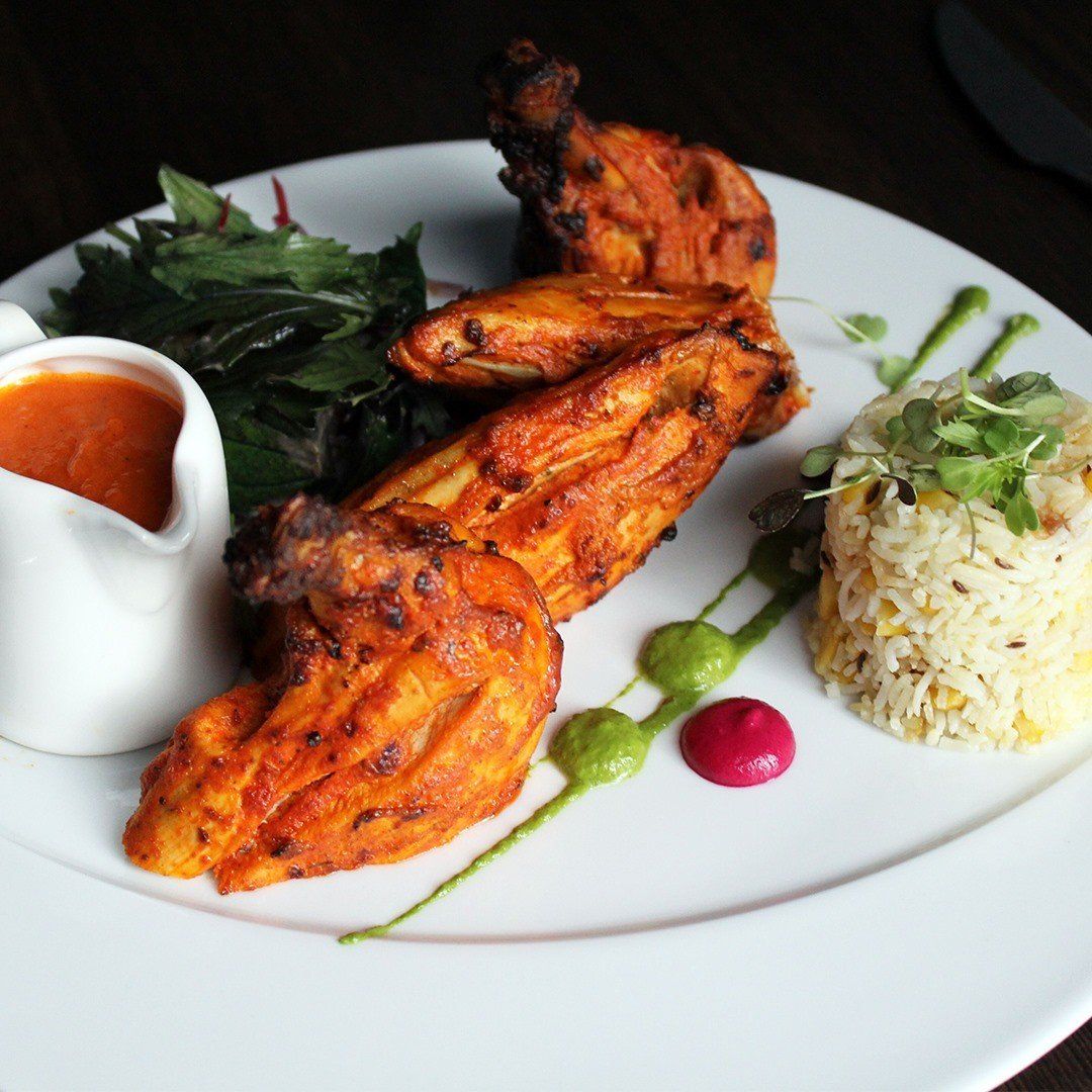 A white plate topped with chicken wings rice and sauce
