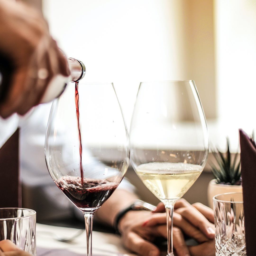 A person pouring wine into a glass on a table
