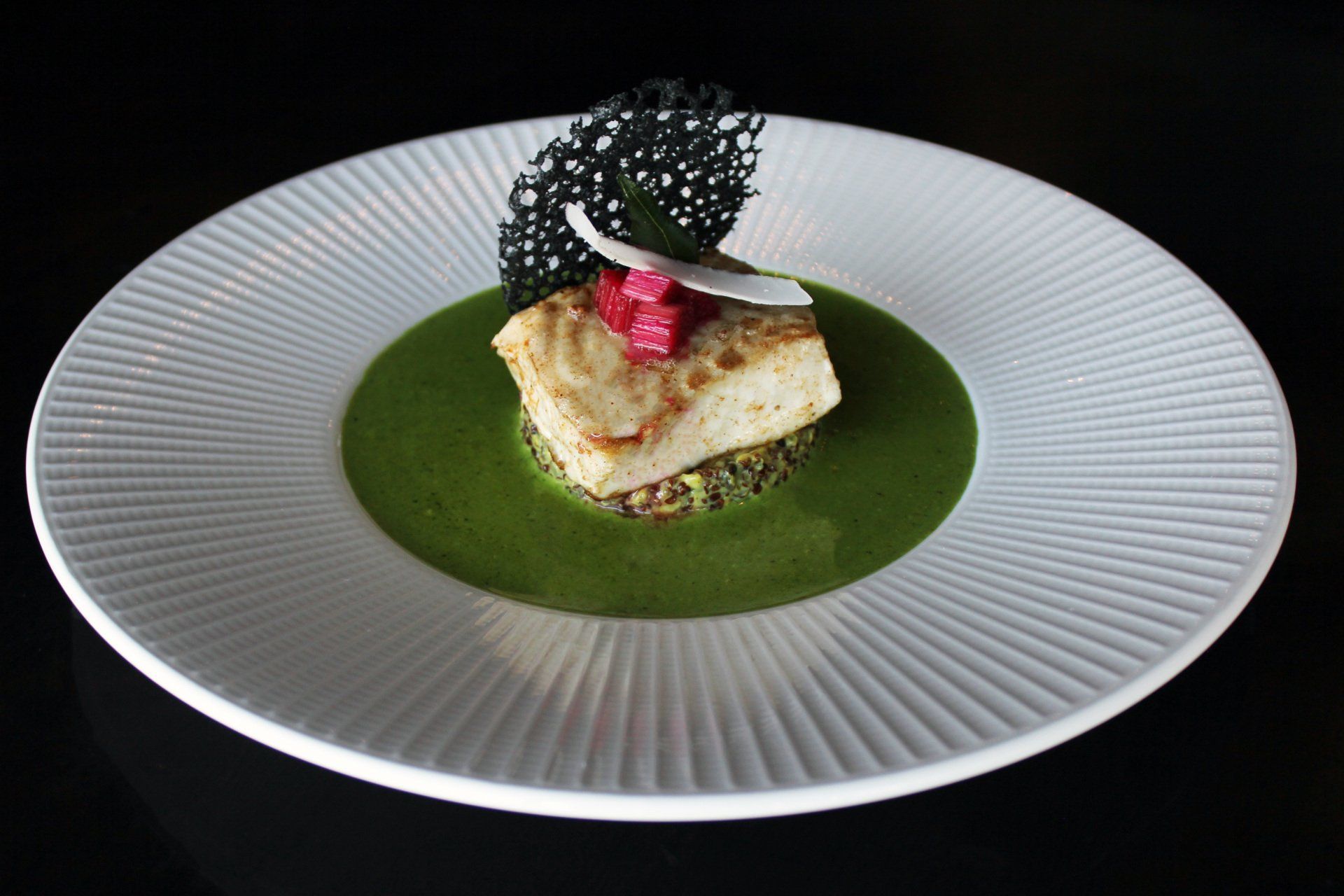 A white plate topped with a piece of food on a green sauce.