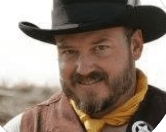 A man with a beard is wearing a cowboy hat and a yellow scarf.
