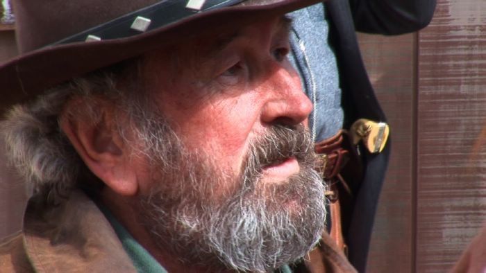 A man with a beard is wearing a cowboy hat.