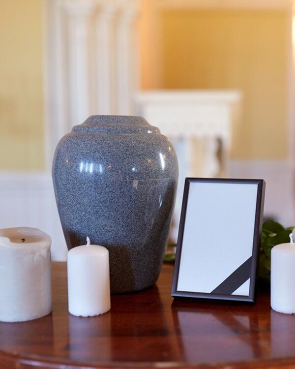Urn, Candle And A Picture Frame On A Table — Quality Cremation Services in Rockhampton, QLD