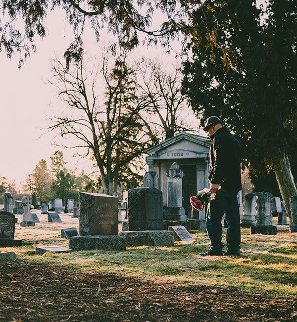 Man Mourning On The Grave Of A Deceased Person — Quality Cremation Services in Rockhampton, QLD