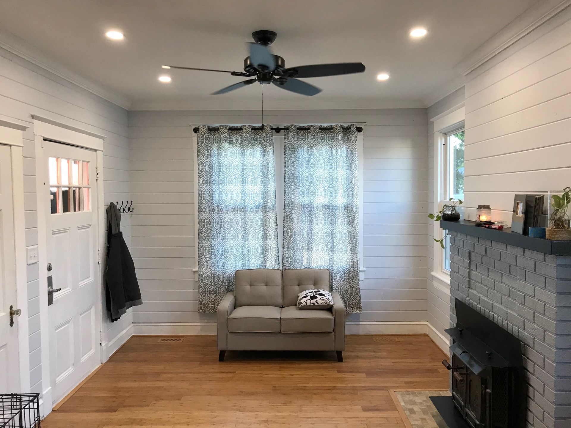 a living room with a couch , fireplace , and ceiling fan .