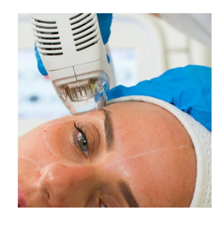 Woman in pink scrubs stands in doorway of medical office; reception desk and treatment room.