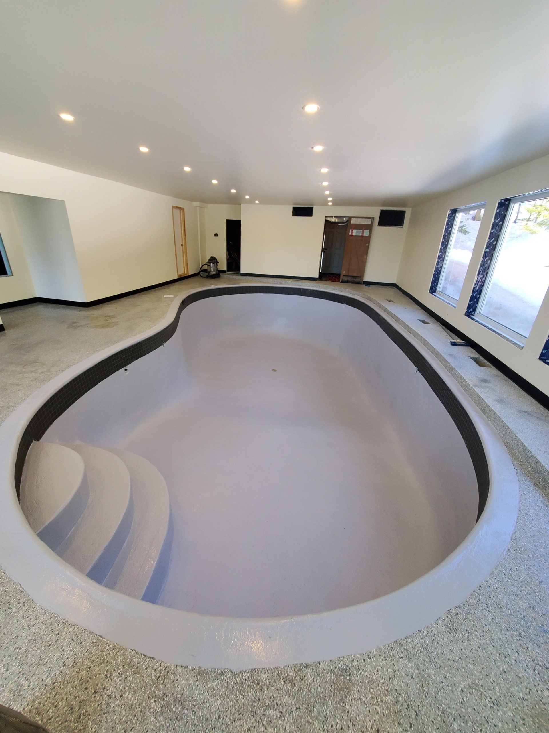 Une grande piscine dans une pièce avec des escaliers qui y mènent.