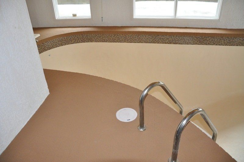 Une piscine marron et blanche avec des escaliers qui y mènent