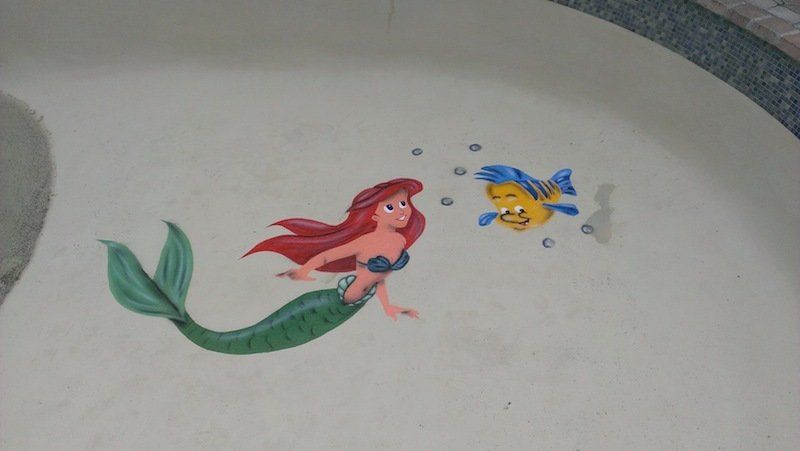 Ariel, aux cheveux roux et à la queue verte, nage avec Polochon sur un mur.