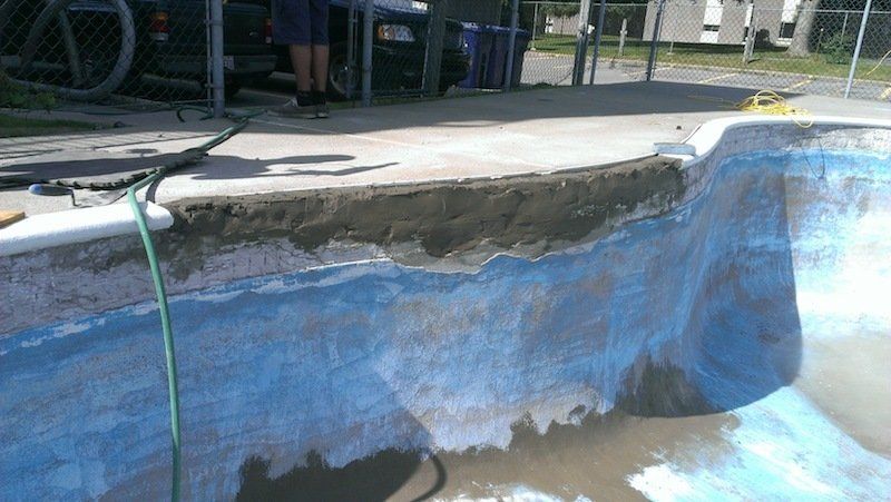 Un homme travaille sur une piscine avec un tuyau attaché.