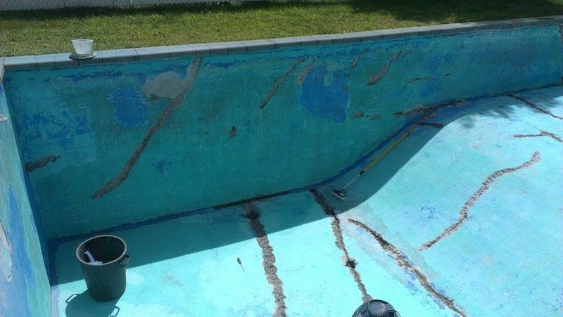 Un seau est posé sur le bord d'une piscine.