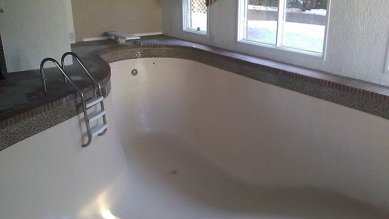 Une piscine vide avec une échelle et une fenêtre.