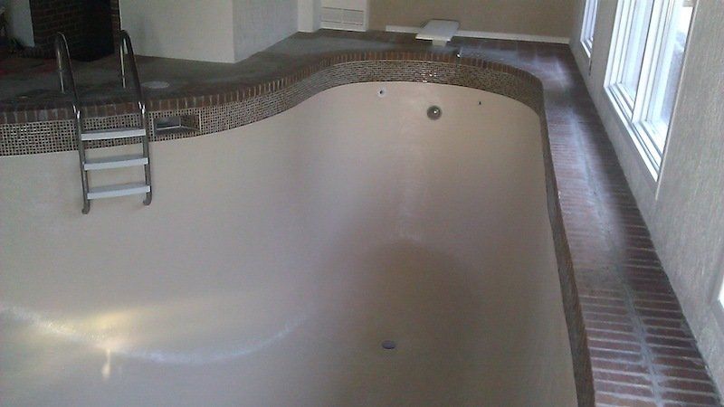 Une piscine vide avec une échelle dans une pièce.