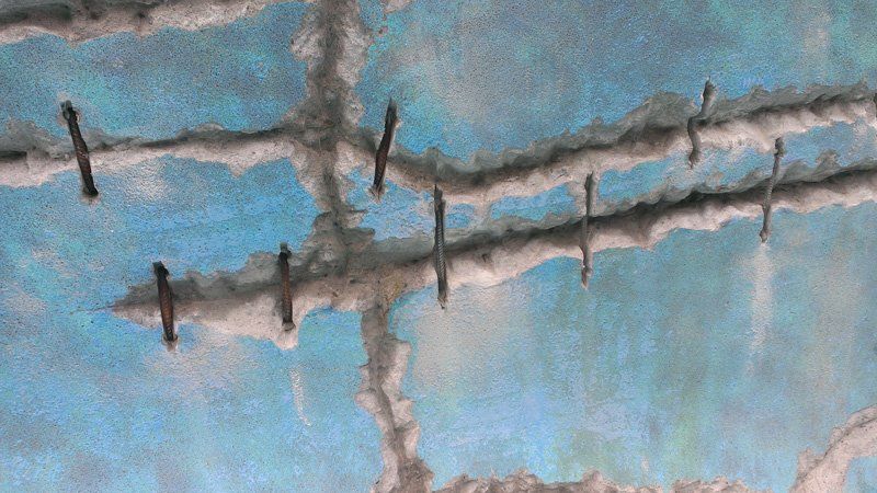 Un gros plan d'une clôture en fil de fer barbelé sur un mur bleu.