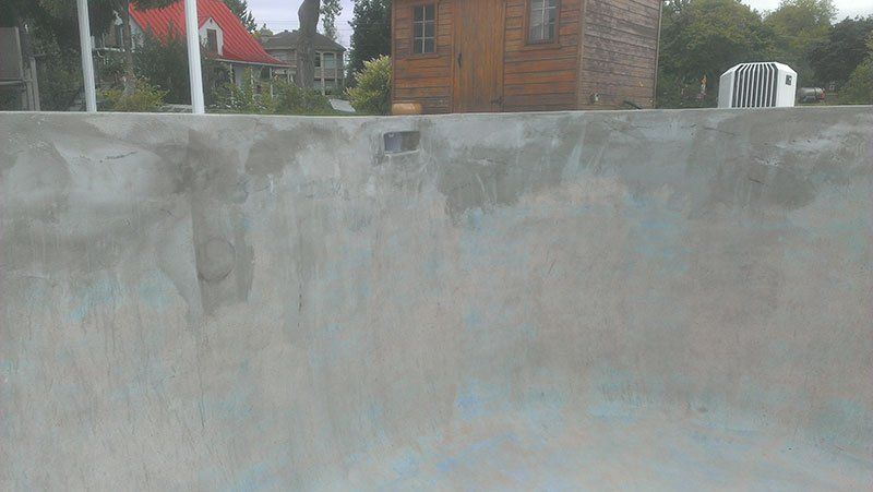 Un gros plan d'un mur en béton avec une maison en arrière-plan.