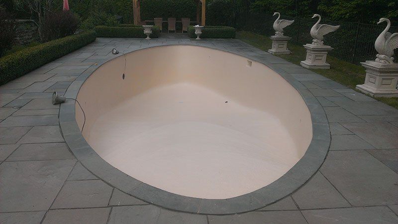 Une grande piscine de forme ovale est entourée de statues de cygnes.