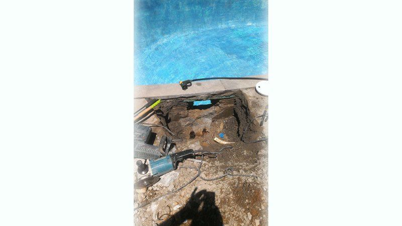 Une personne creuse un trou dans le sol à côté d'une piscine.