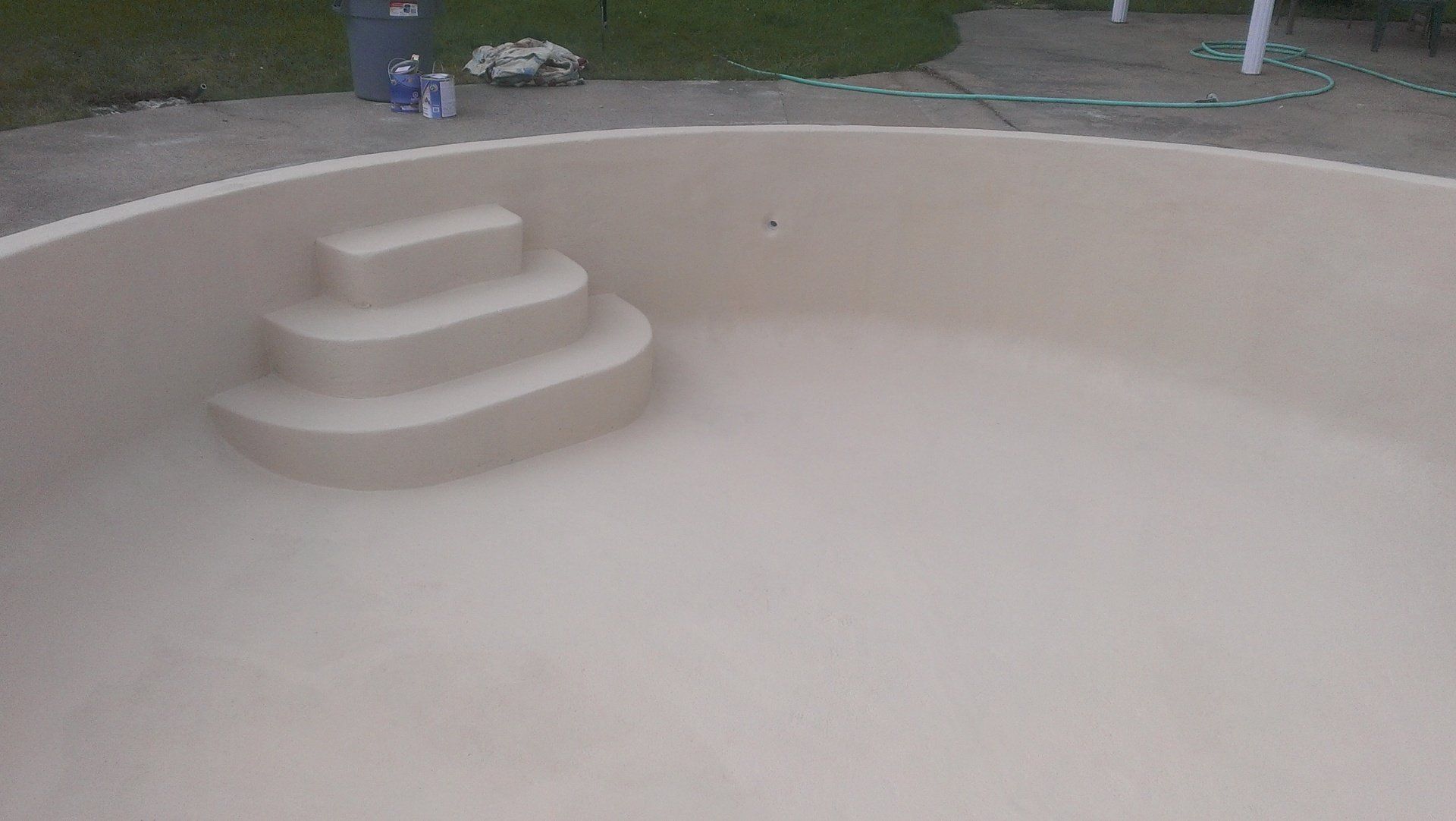 Piscine ronde vide de couleur beige avec marches intégrées.