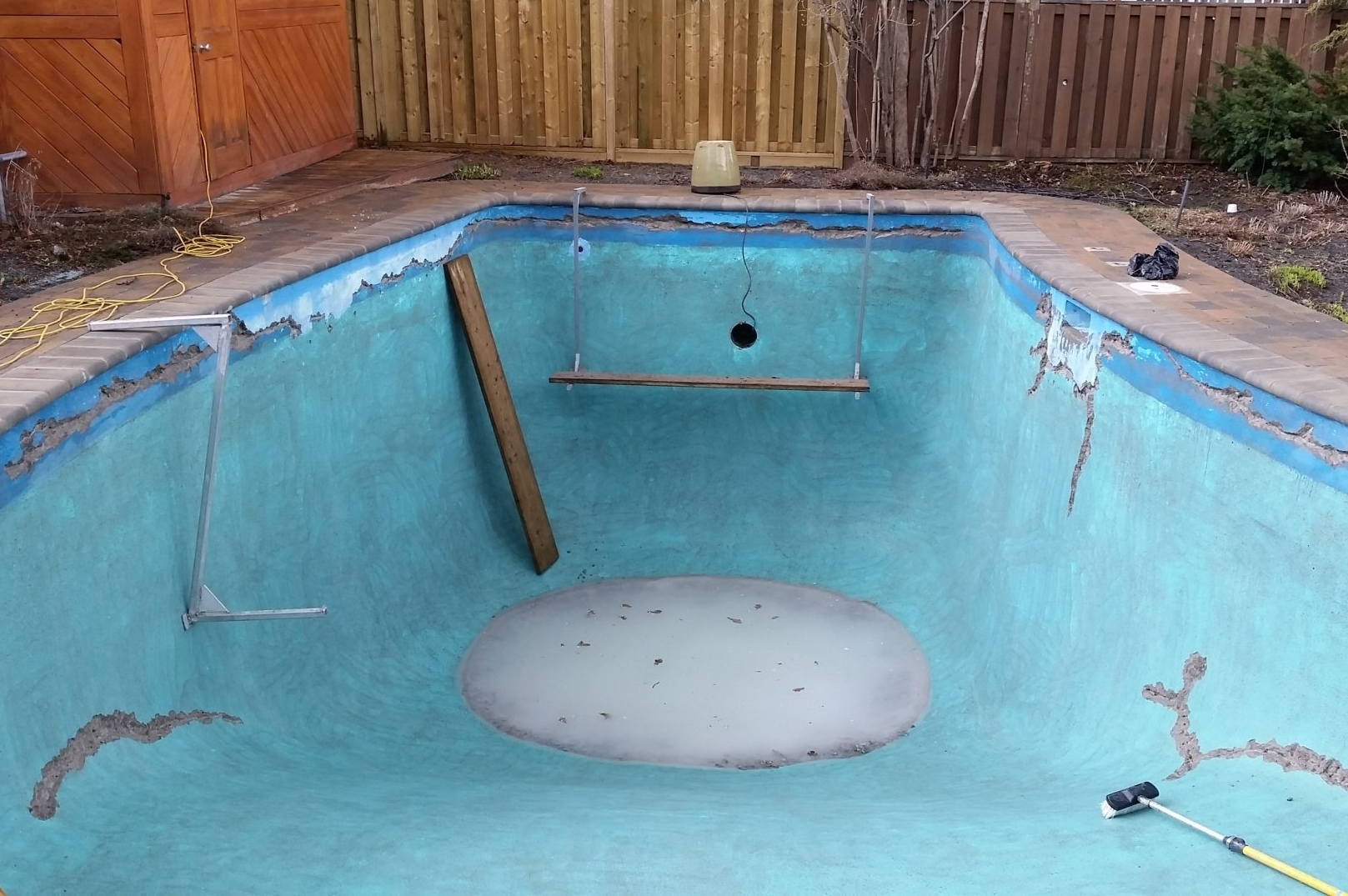 Une piscine vide avec une clôture en bois en arrière-plan