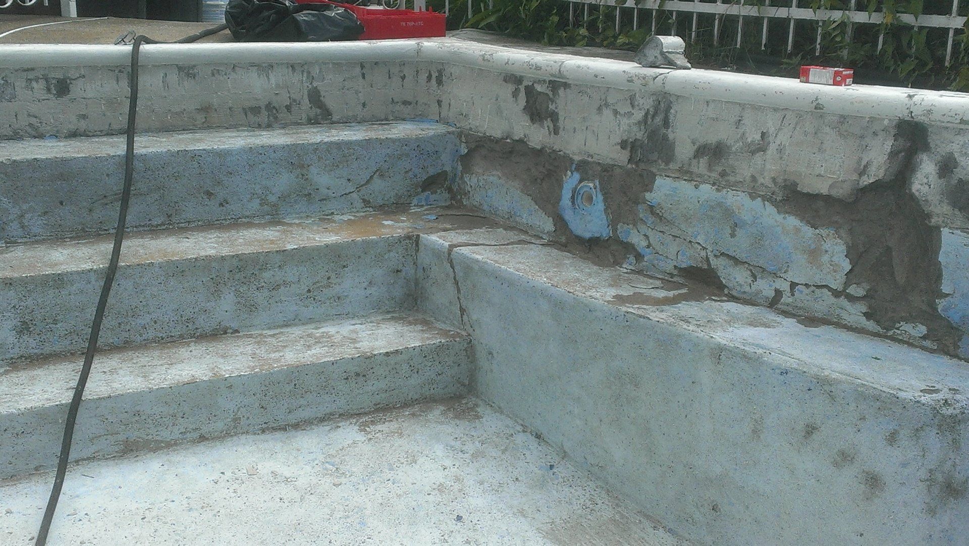 Escaliers de piscine en béton, peinture écaillée. Couleurs bleu, gris et blanc. Aménagement extérieur.