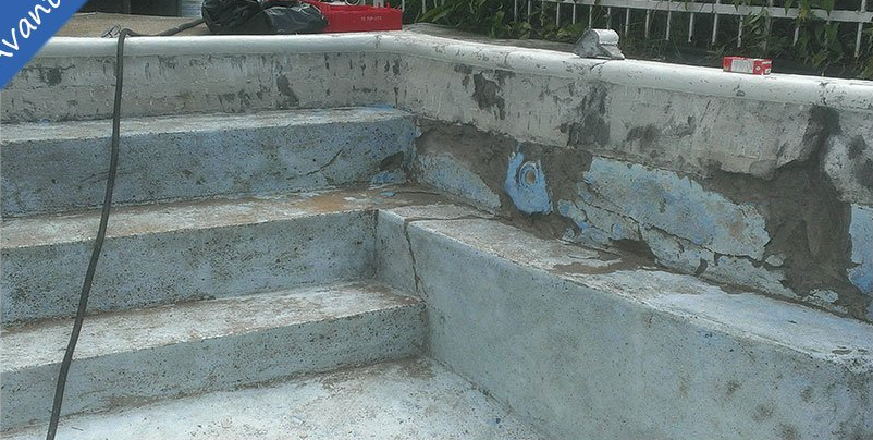 Marches en béton d'une piscine présentant des fissures et des détériorations.