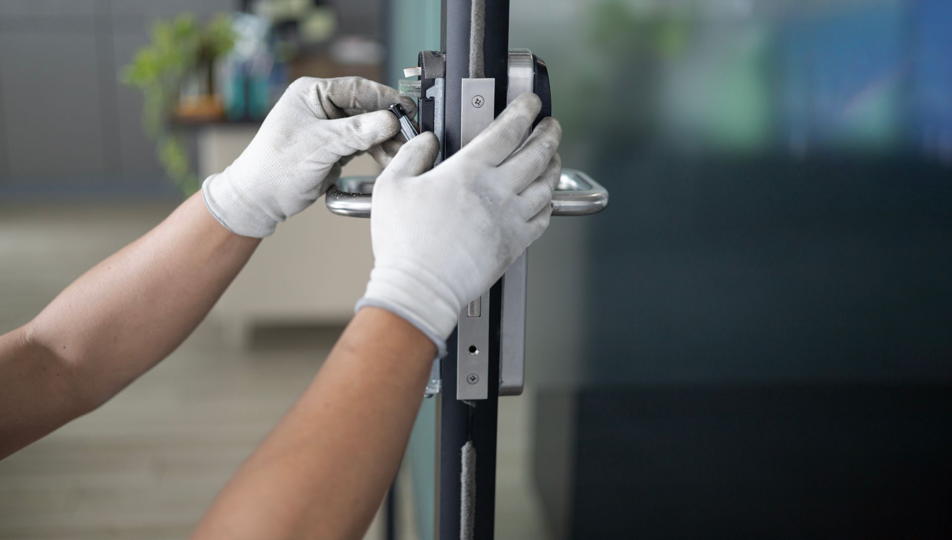 Gloved hands adjusting a door lock on a glass door panel Gloved hands adjusting a door lock on a glass door panel