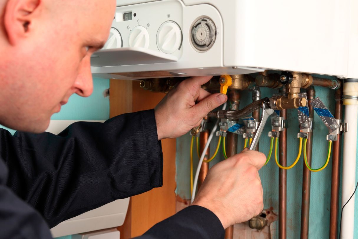 A man fixing a boiler with tools.
