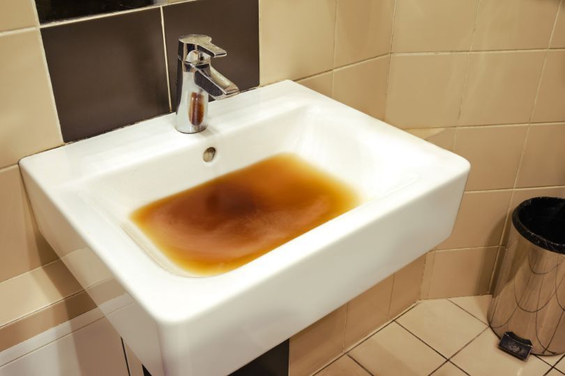 Sink that needs immediate repair because of brown liquid.