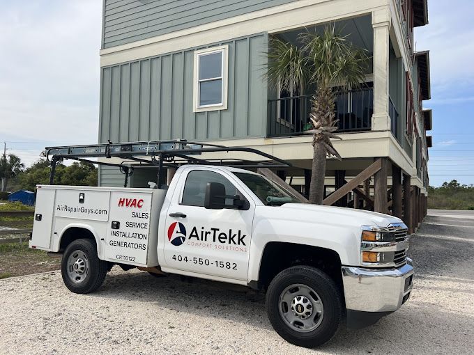 A white AirTekk truck is parked in front of a house.