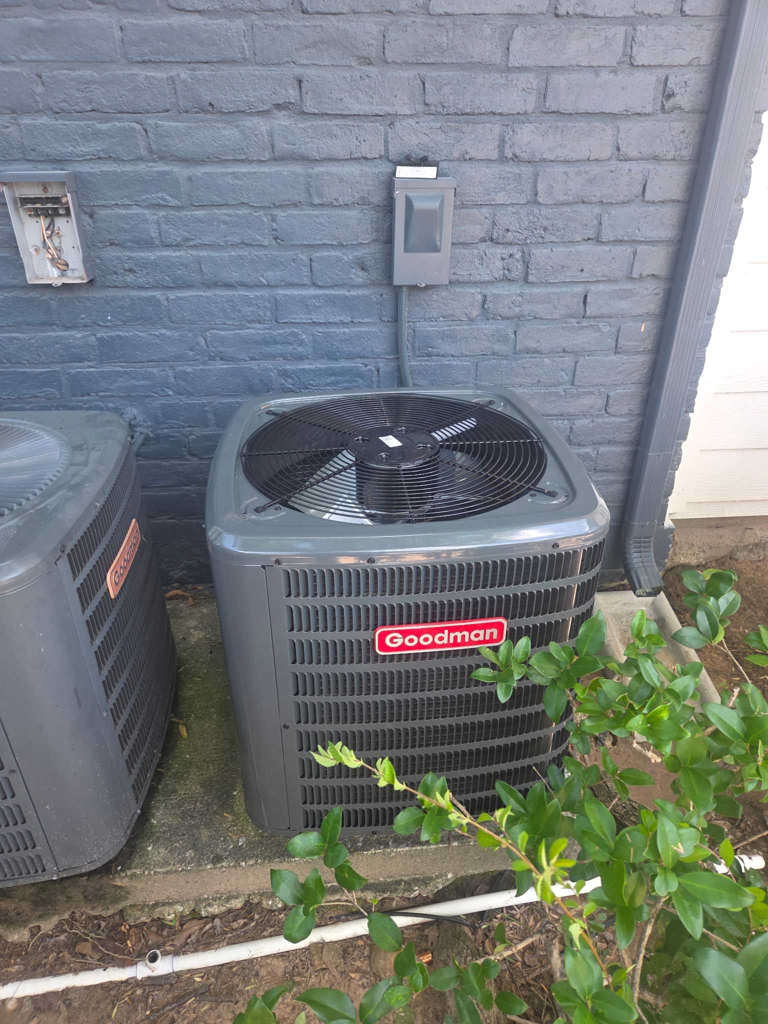 A large air conditioner is sitting on the side of a brick building.