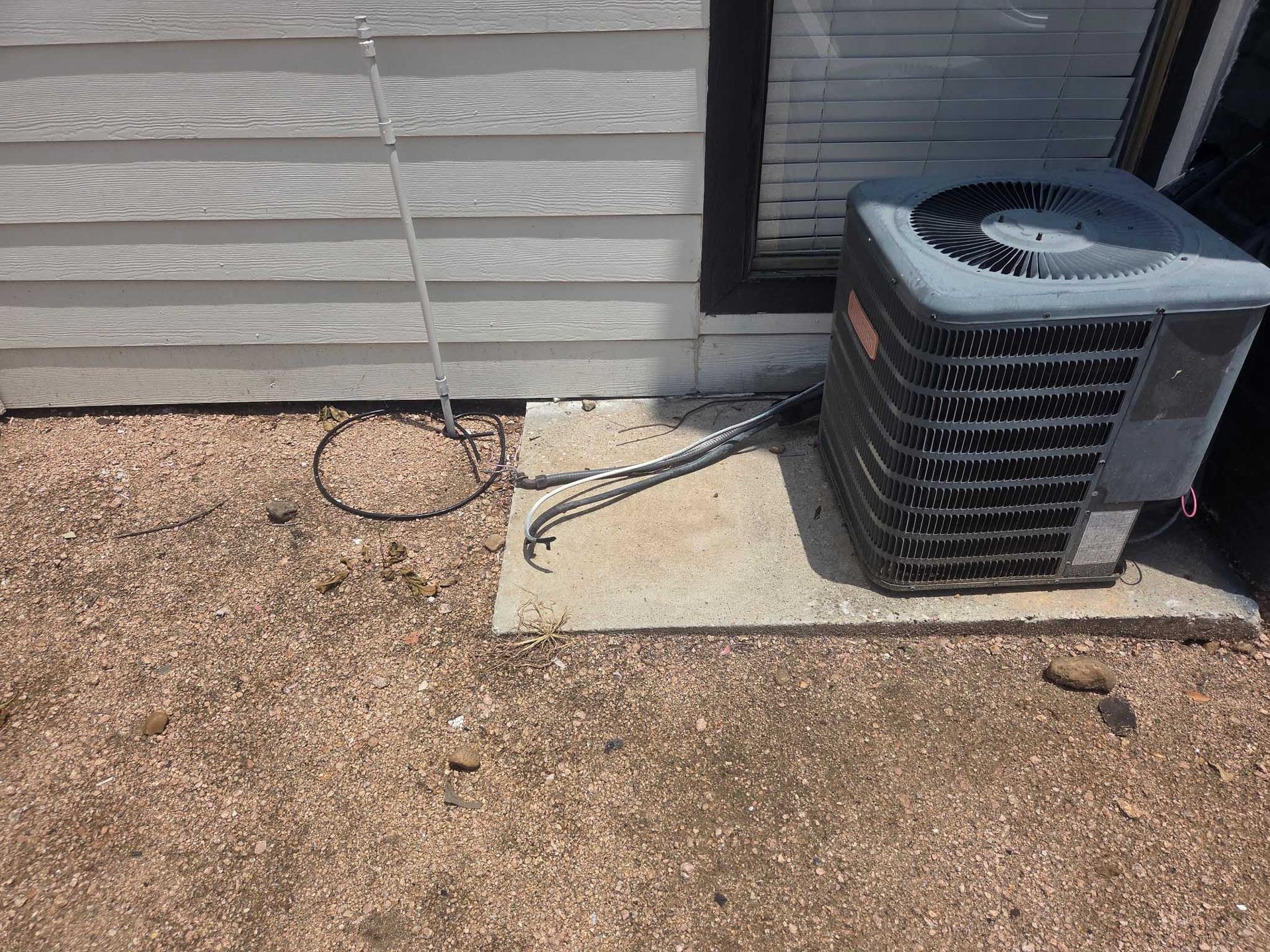 An air conditioner is sitting on the ground in front of a house.