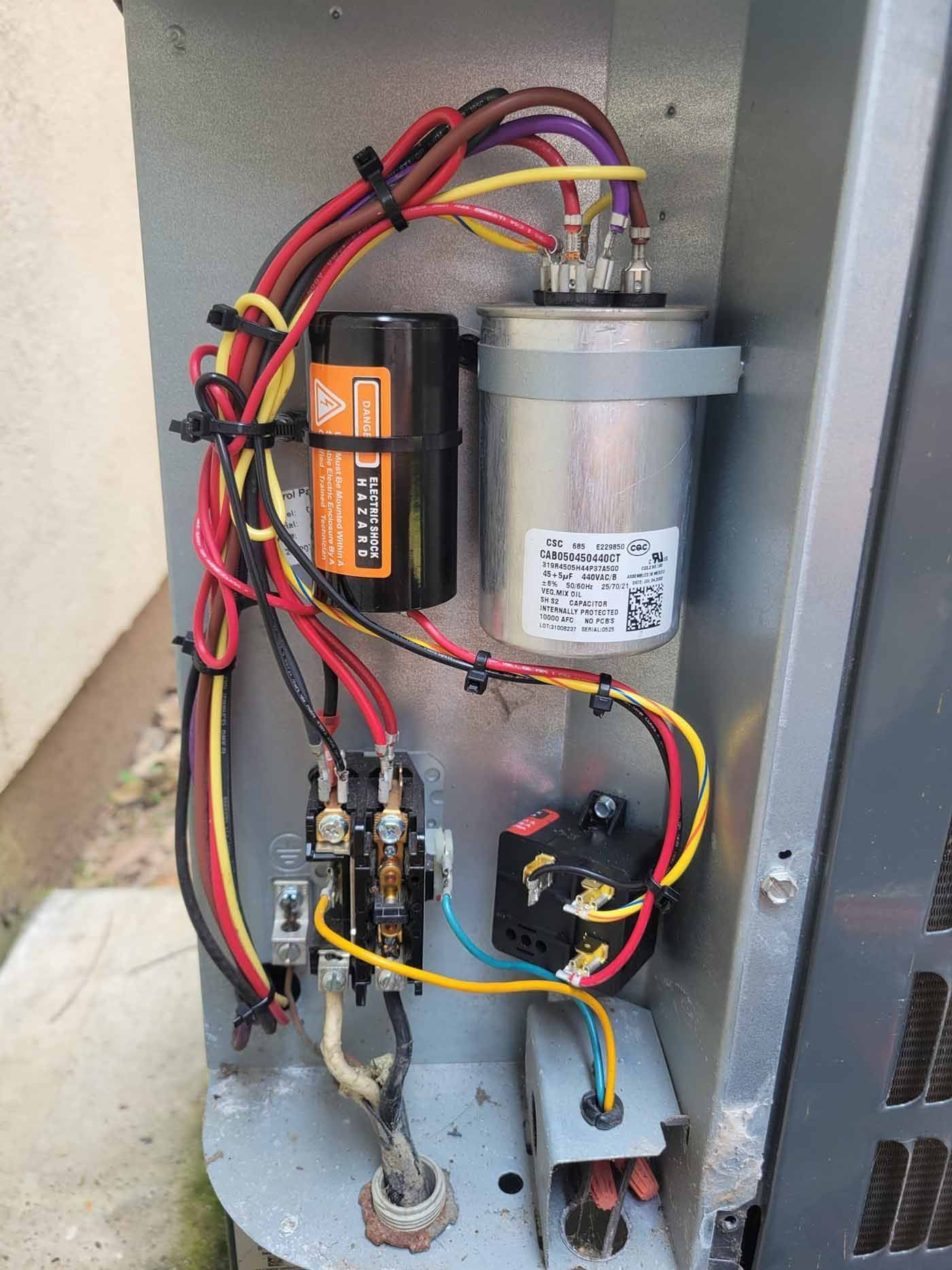 The inside of an air conditioner with a lot of wires coming out of it.